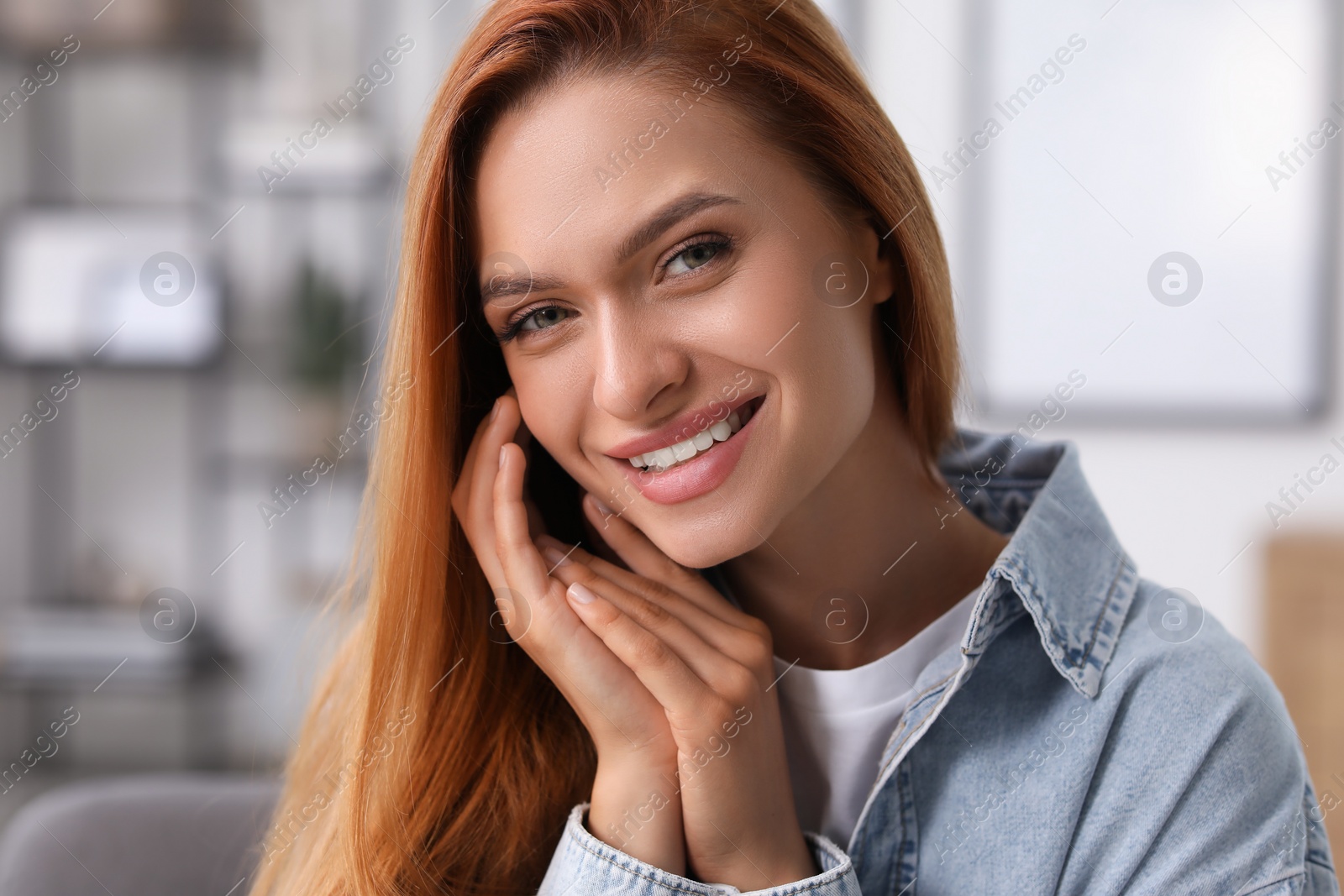 Photo of Portrait of beautiful young woman with red hair at home. Attractive lady smiling and looking into camera