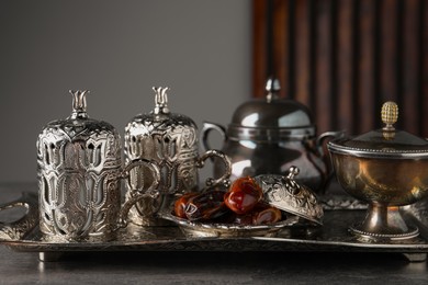 Tea and date fruits served in vintage tea set on grey textured table