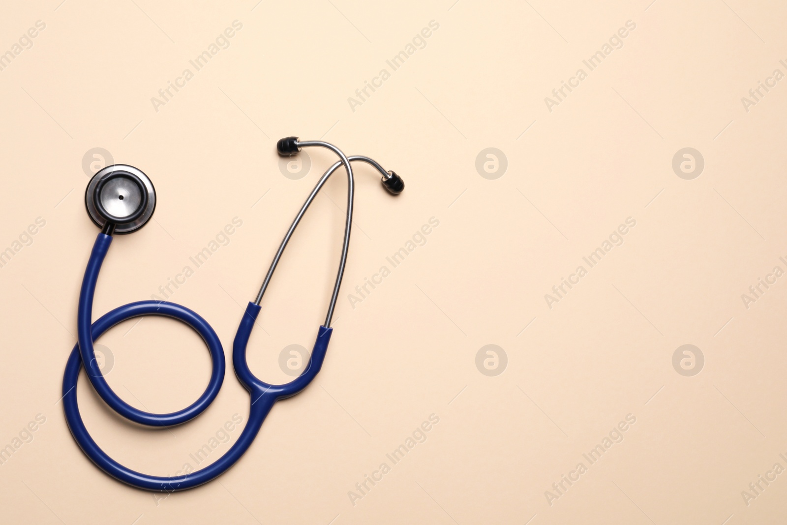 Photo of Stethoscope on beige background, top view. Space for text