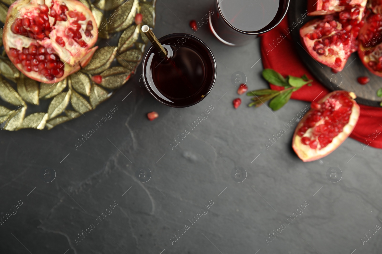 Photo of Glasses of pomegranate juice and fresh fruits on black table, flat lay. Space for text