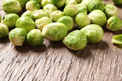 Photo of Fresh Brussels sprouts on wooden table, closeup. Space for text