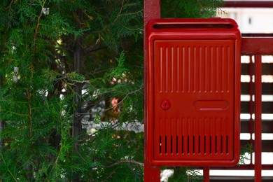 Photo of Red beautiful metal letter box near tree outdoors