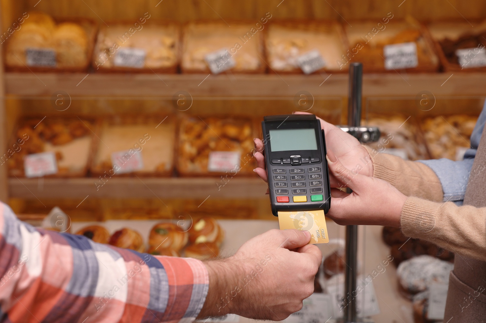 Photo of Man using bank terminal for credit card payment in bakery, closeup. Space for text