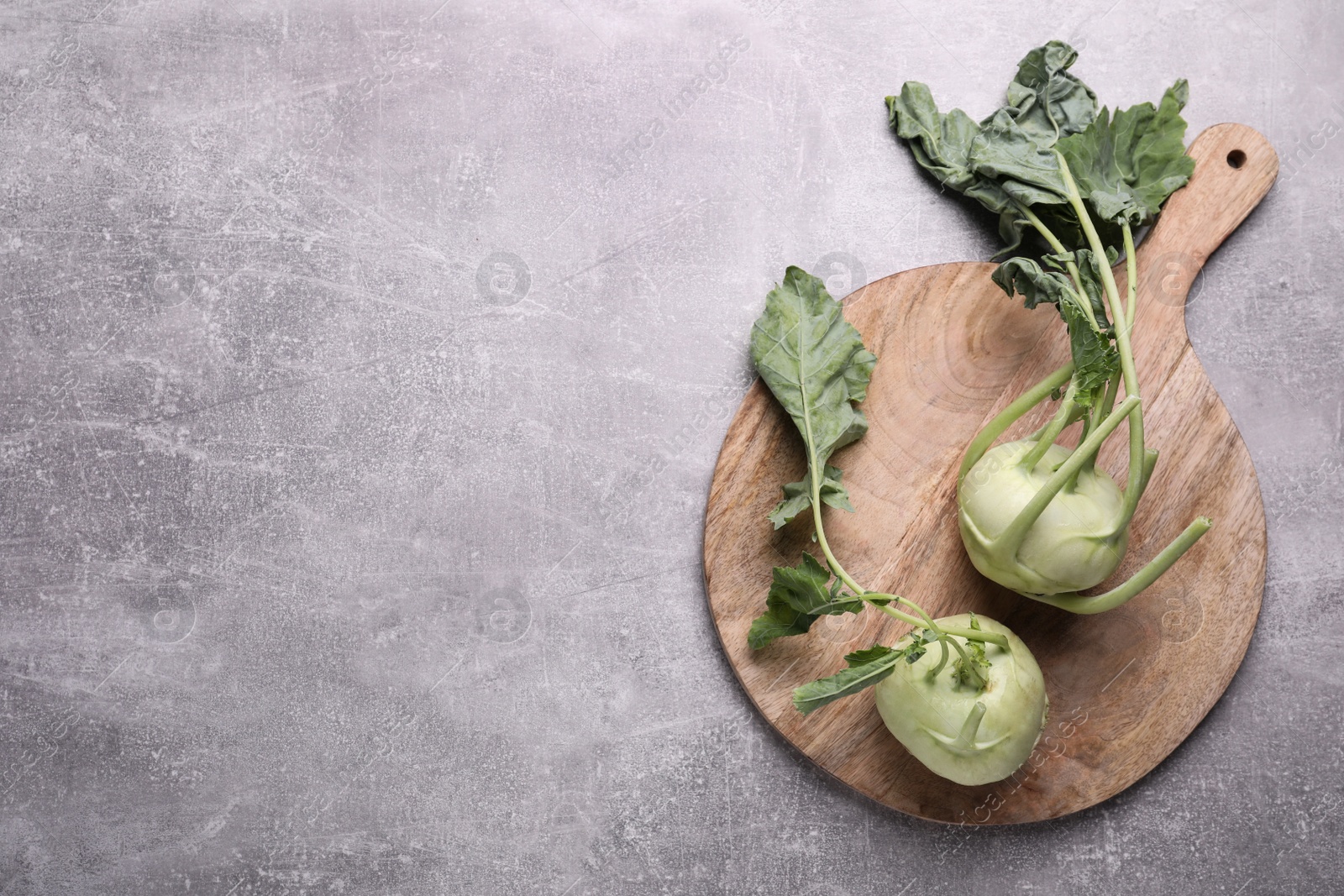 Photo of Whole ripe kohlrabi plants on grey table, top view. Space for text