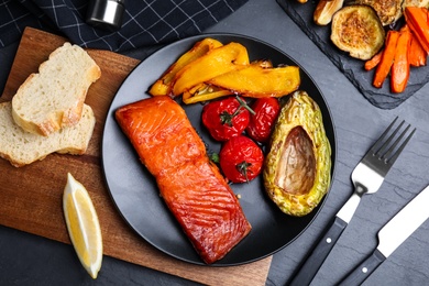 Photo of Delicious cooked salmon and vegetables served on black table, flat lay. Healthy meals from air fryer