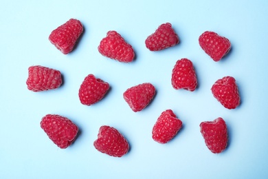 Flat lay composition with delicious ripe raspberries on blue background