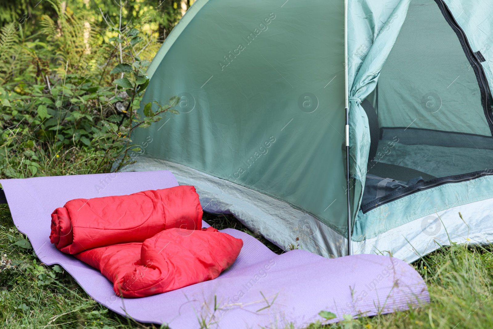 Photo of Sleeping bag and mat near camping tent outdoors