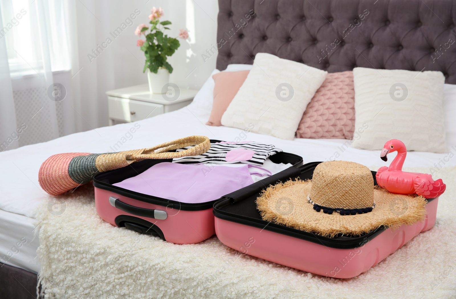 Photo of Modern suitcase with clothes packed for journey on bed indoors