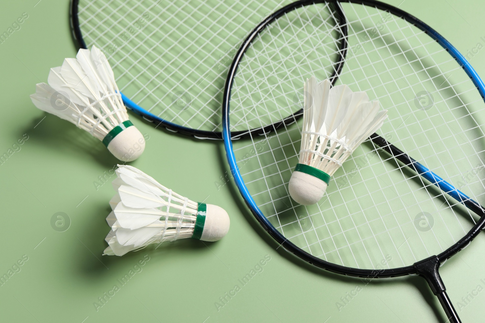 Photo of Feather badminton shuttlecocks and rackets on green background, above view