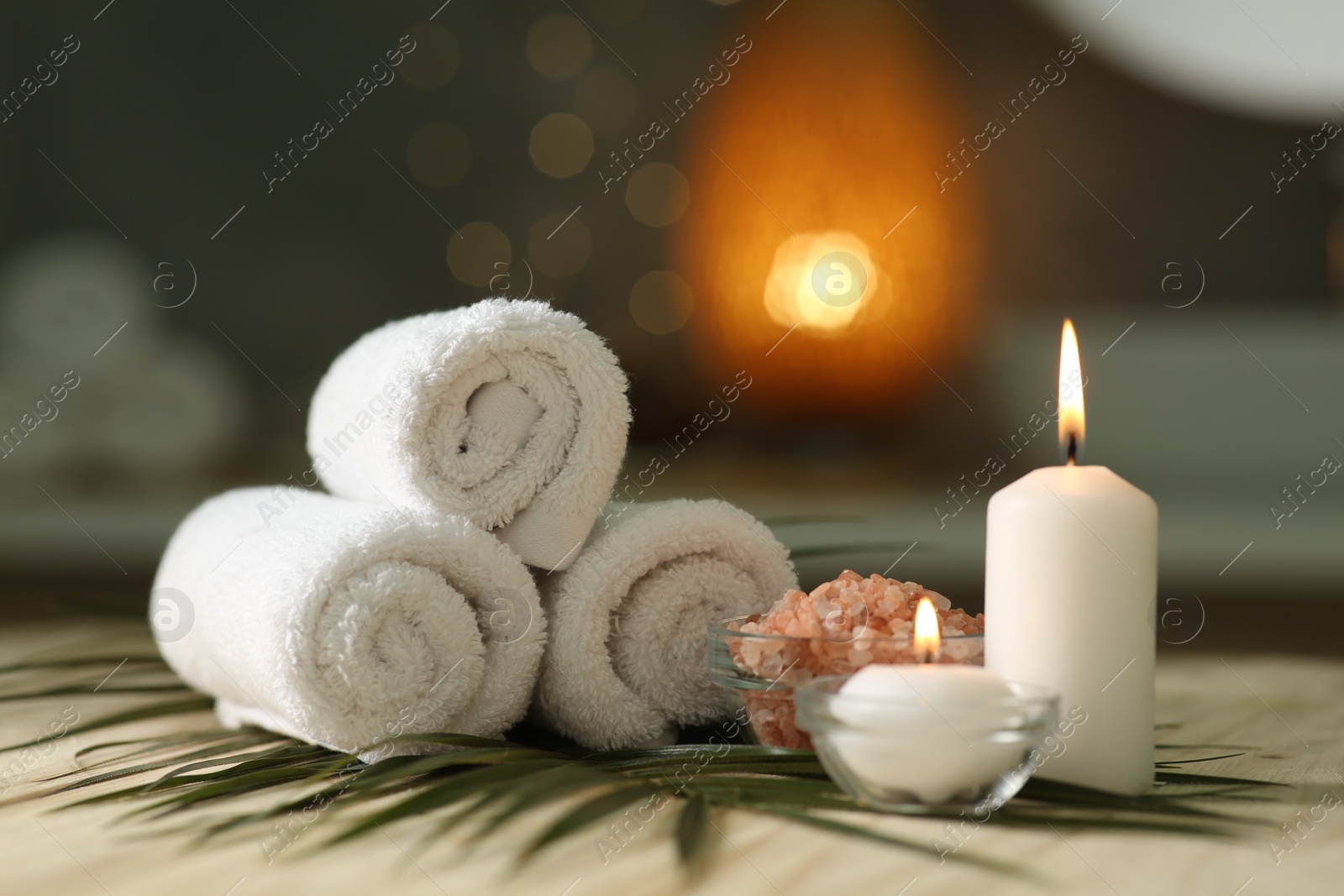 Photo of Composition with different spa products and burning candles on wooden table indoors