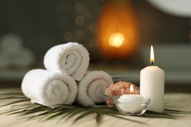 Composition with different spa products and burning candles on wooden table indoors
