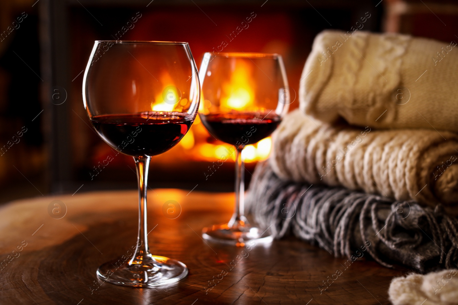 Photo of Glasses of wine, knitwear and blurred fireplace on background