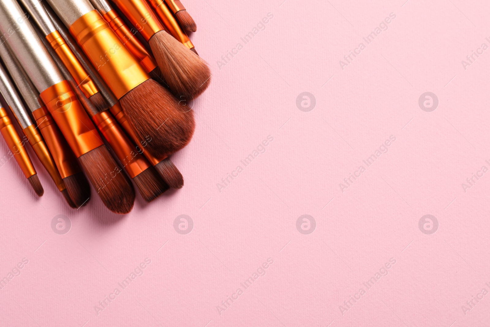 Photo of Set of makeup brushes on pink background, above view. Space for text