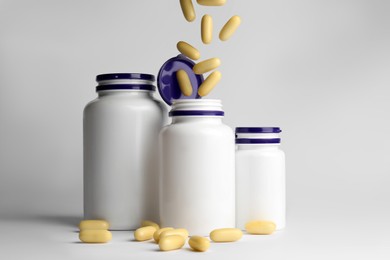 Photo of Pills falling into medical bottles on white background