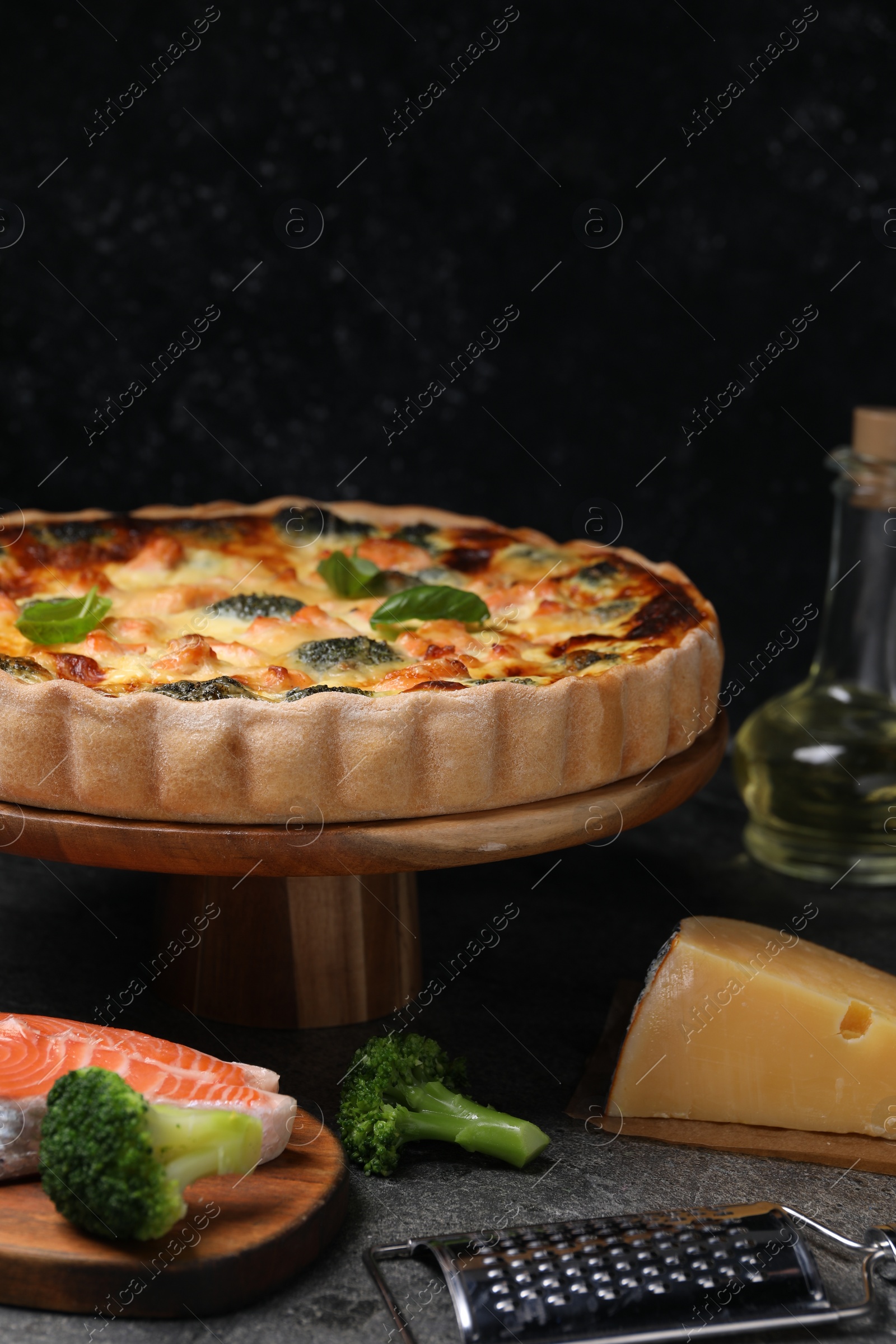 Photo of Delicious homemade quiche and ingredients on black table