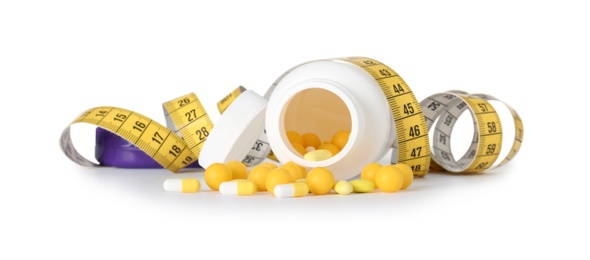 Weight loss pills and bottle with measuring tape on white background