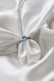 Beautiful ring with light blue gemstone on white fabric. Luxury jewelry
