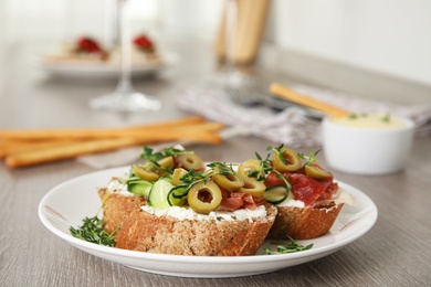 Plate of delicious bruschettas with prosciutto on grey wooden table