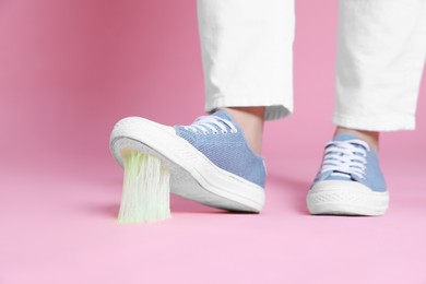 Photo of Person stepping into chewing gum on pink background, closeup