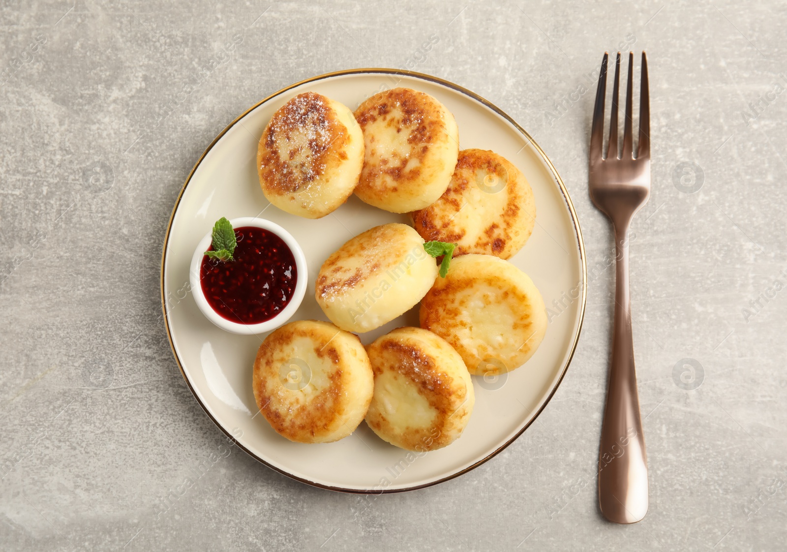 Photo of Delicious cottage cheese pancakes with jam and icing sugar on light grey table, flat lay