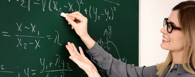 Image of Happy teacher writing on chalkboard in classroom. Banner design