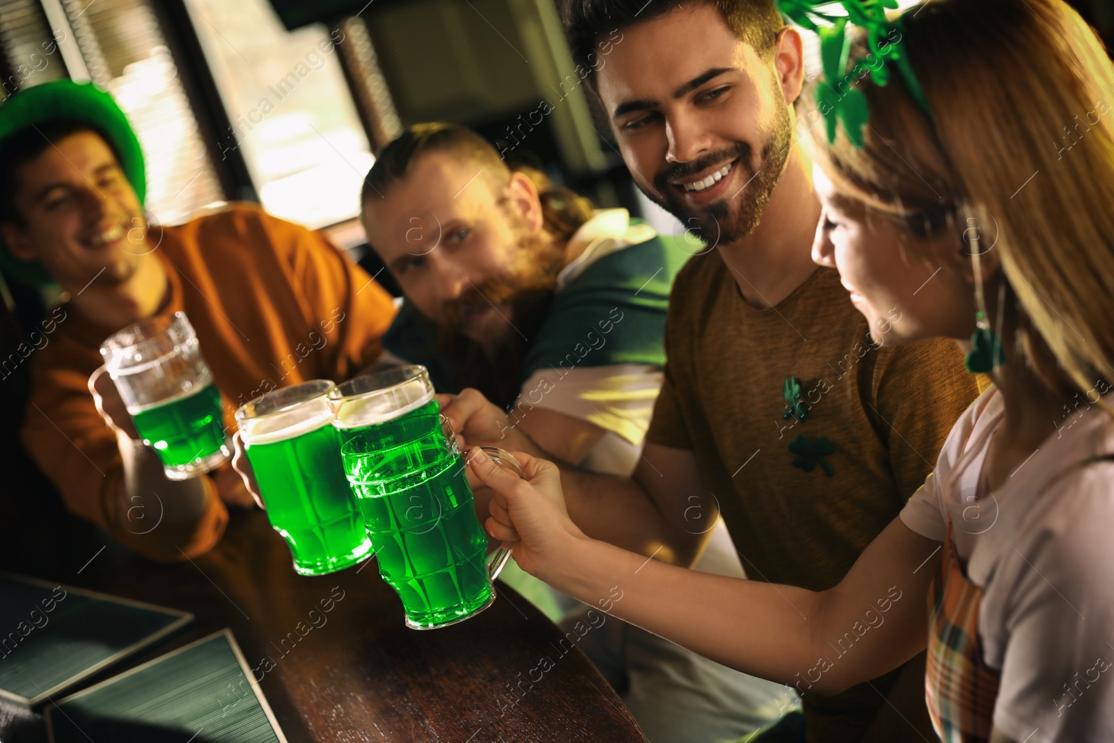 Photo of Group of friends toasting with green beer in pub. St. Patrick's Day celebration