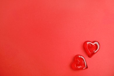 Photo of Sweet heart shaped jelly candies on red background, flat lay. Space for text