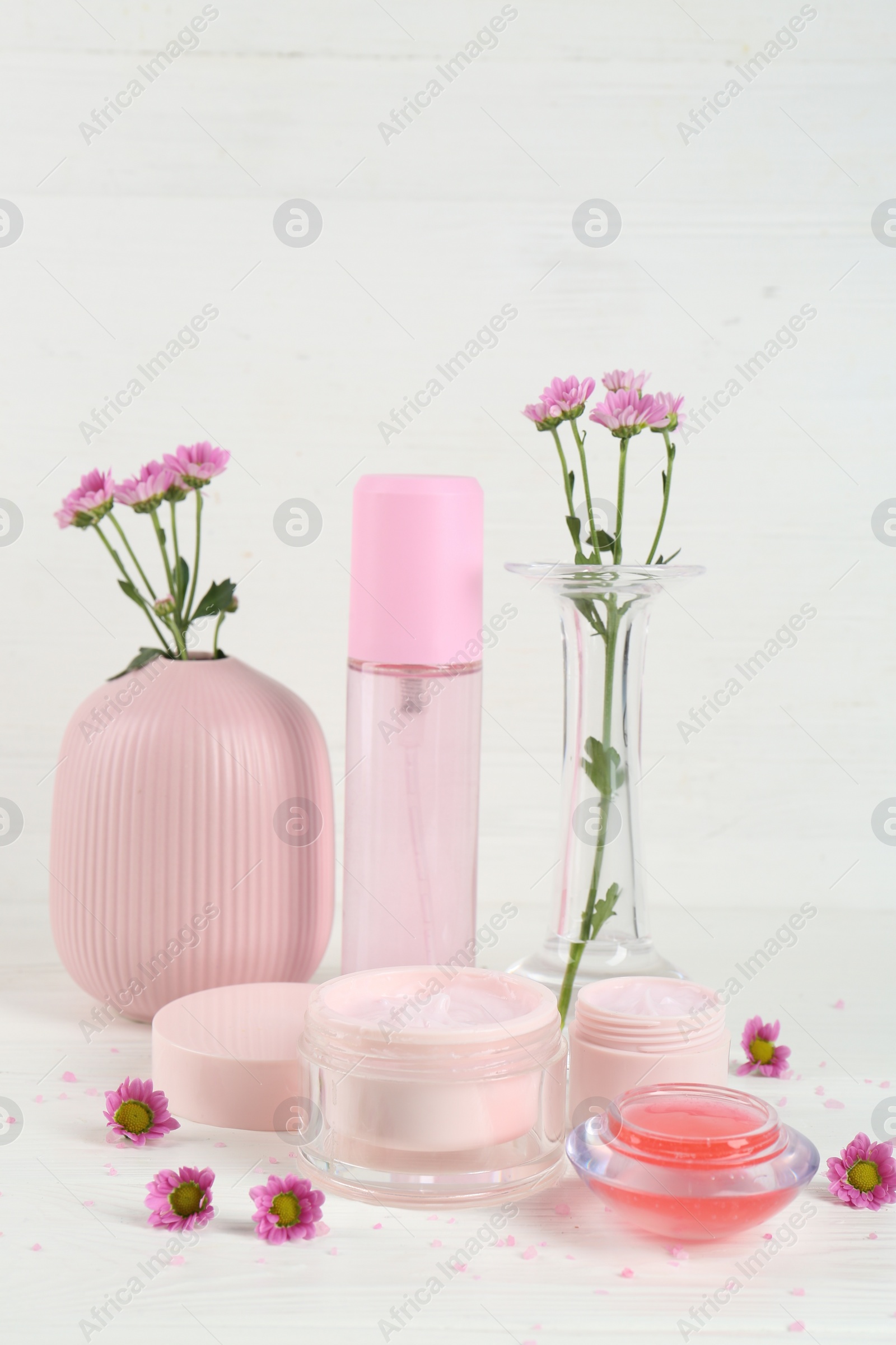 Photo of Homemade cosmetic products and beautiful flowers on white table
