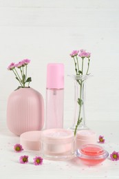 Homemade cosmetic products and beautiful flowers on white table