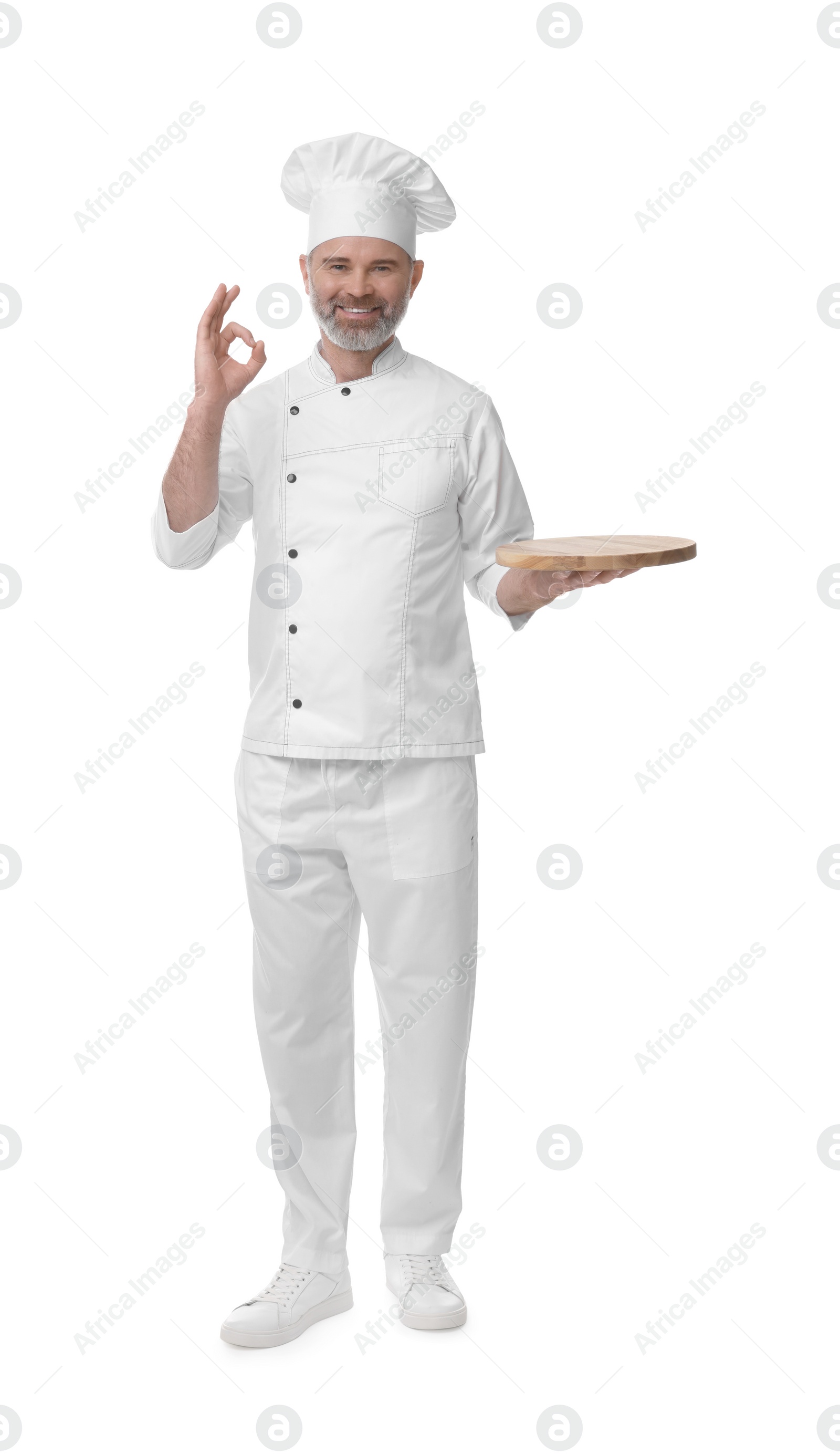 Photo of Happy chef in uniform with wooden board showing OK gesture on white background