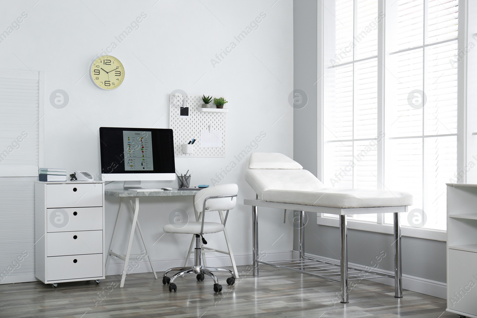 Photo of Modern medical office interior with computer and examination table