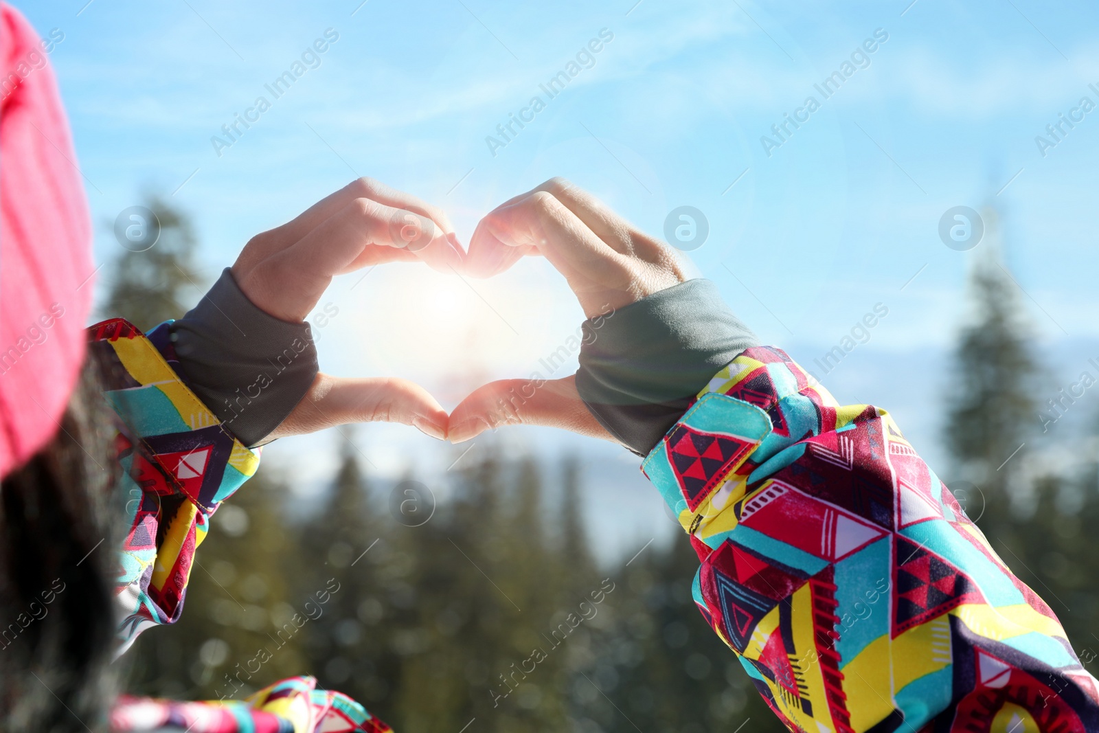 Photo of Woman making heart with her hands in mountains, closeup. Winter vacation