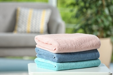 Photo of Stack of folded clean soft towels on table indoors. Space for text