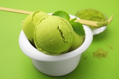 Photo of Tasty matcha ice cream in bowl on light green background, closeup