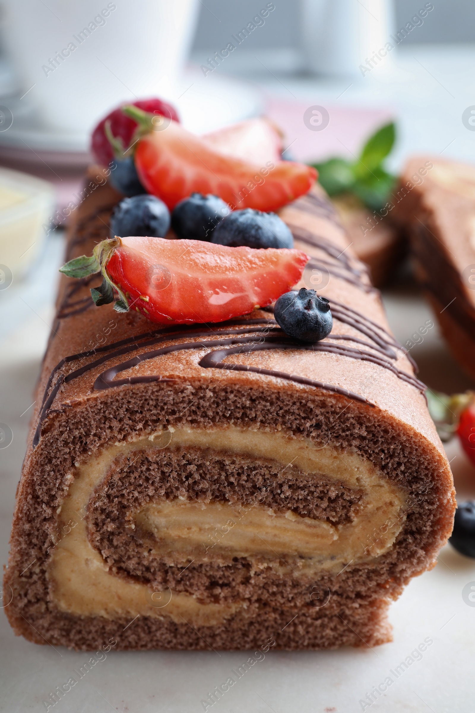 Photo of Tasty chocolate cake roll with cream and berries, closeup