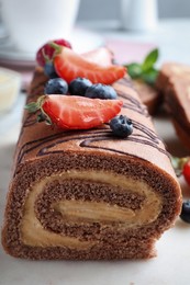 Tasty chocolate cake roll with cream and berries, closeup