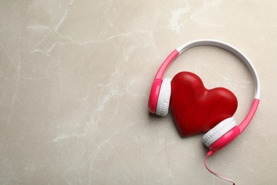 Photo of Decorative heart with modern headphones on table, top view. Space for text