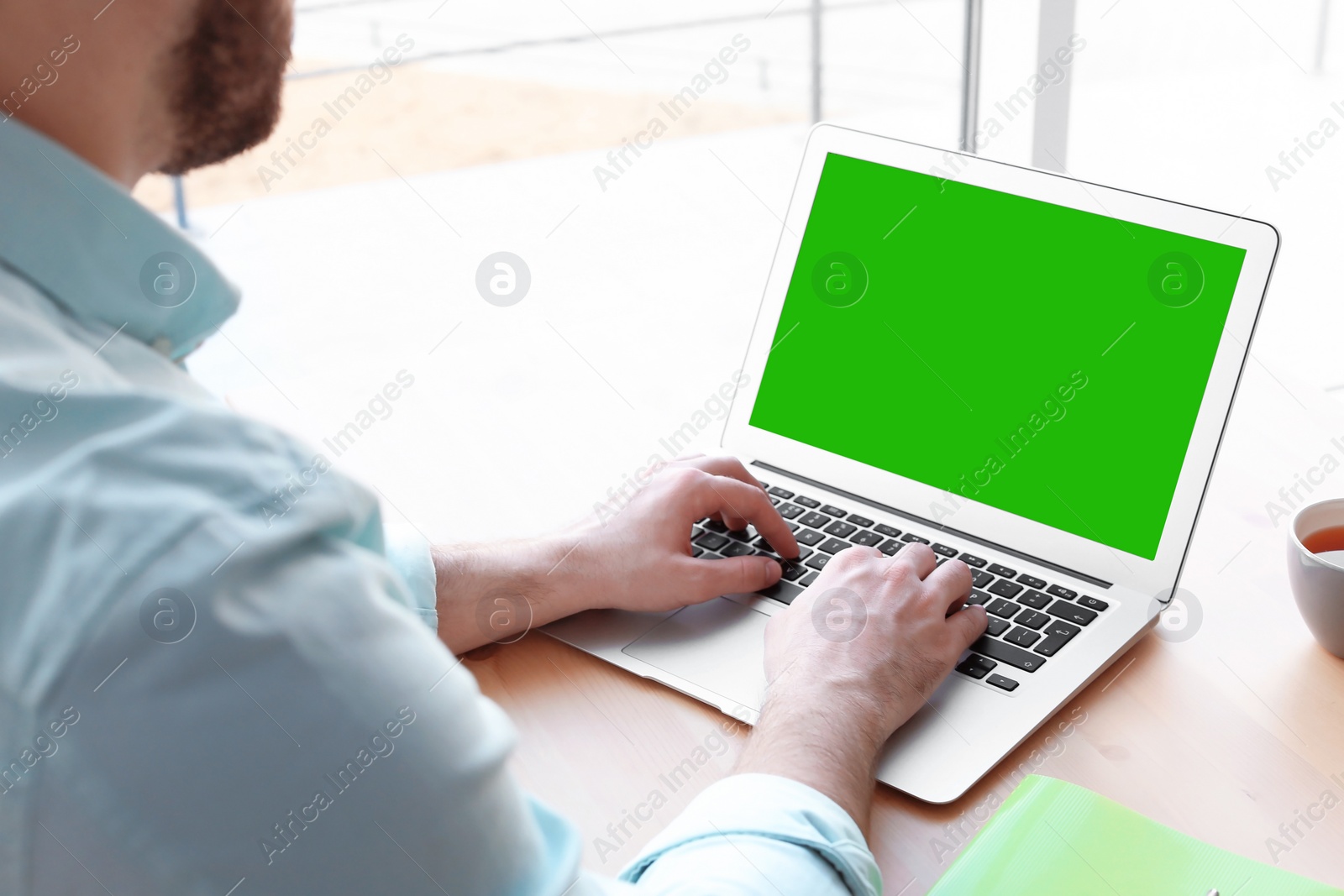 Image of Young man using laptop at desk, closeup. Device display with chroma key