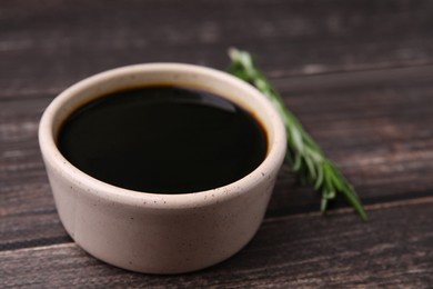 Bowl with balsamic vinegar on wooden table, closeup