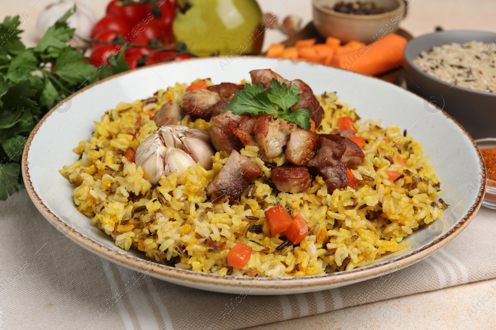 Photo of Delicious pilaf with meat, carrot and garlic on beige table, closeup