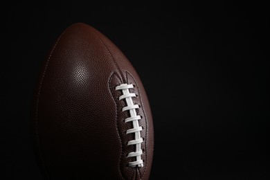 Photo of American football ball on black background, closeup. Space for text