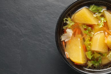 Photo of Bowl of tasty turnip soup on black table, top view. Space for text