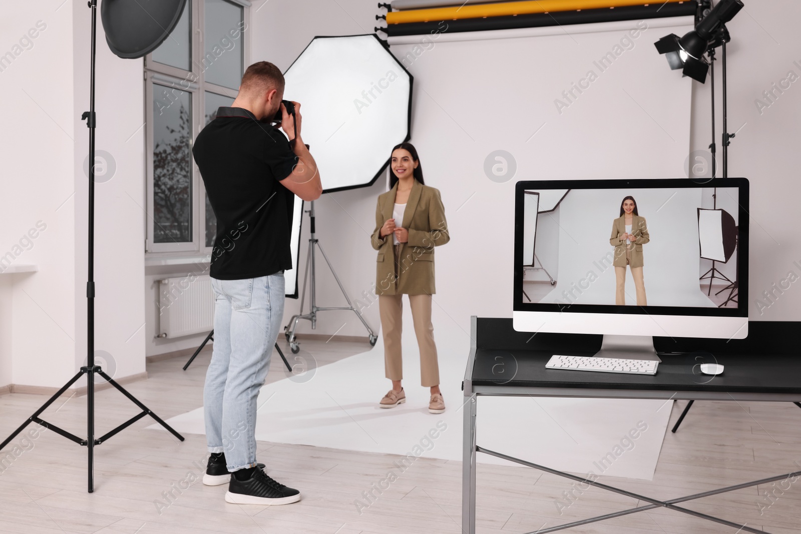 Photo of Professional photographer working with beautiful model in modern photo studio, selective focus