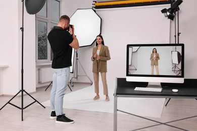 Photo of Professional photographer working with beautiful model in modern photo studio, selective focus