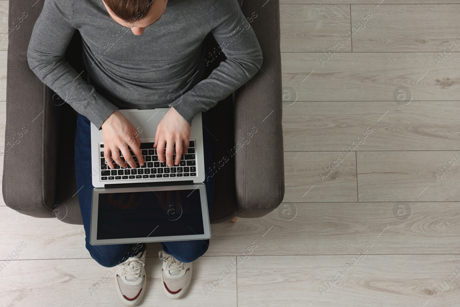 Photo of Man working with laptop in armchair, top view. Space for text