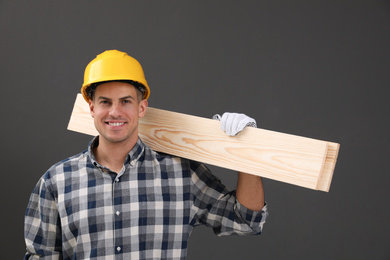 Handsome carpenter with wooden planks on dark background