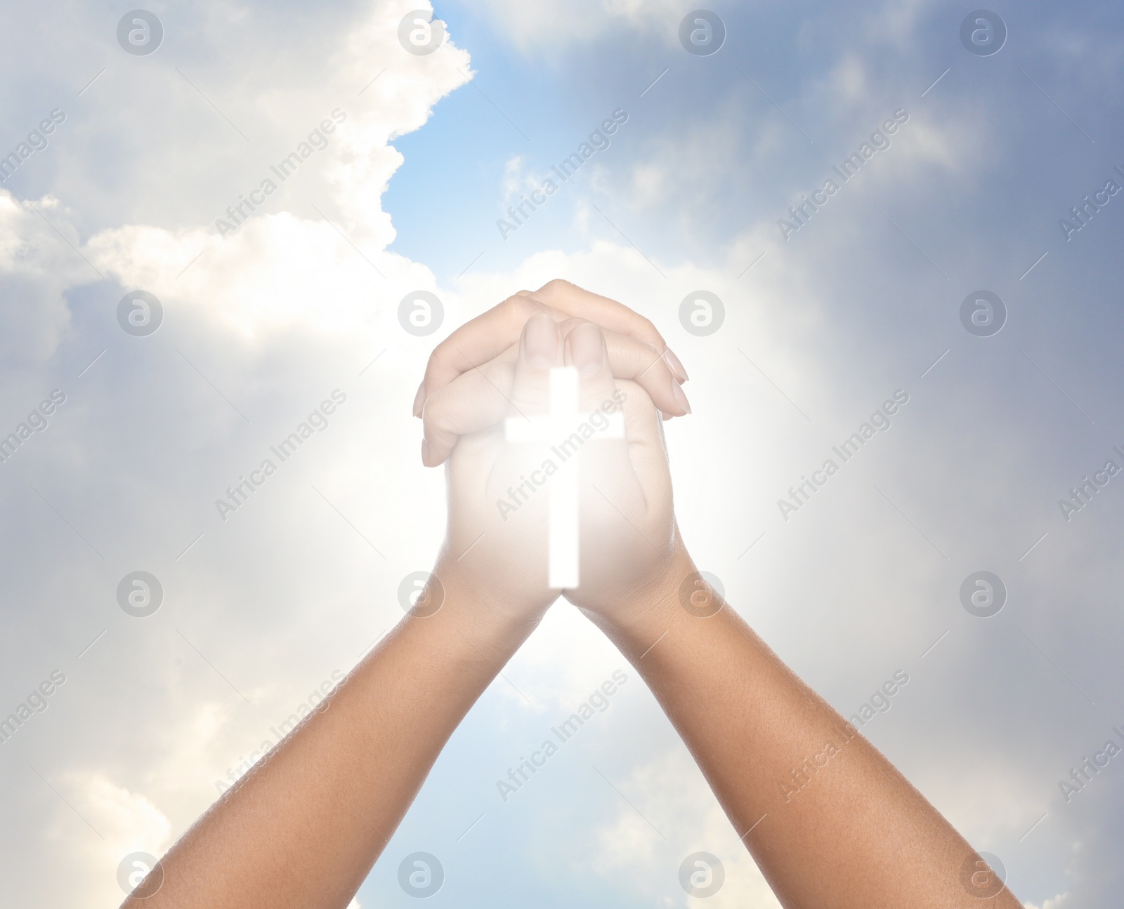 Image of Religion. Christian woman with glowing cross praying against sky, closeup