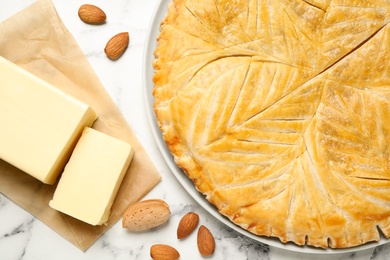Photo of Traditional galette des rois and ingredients on white marble table, flat lay