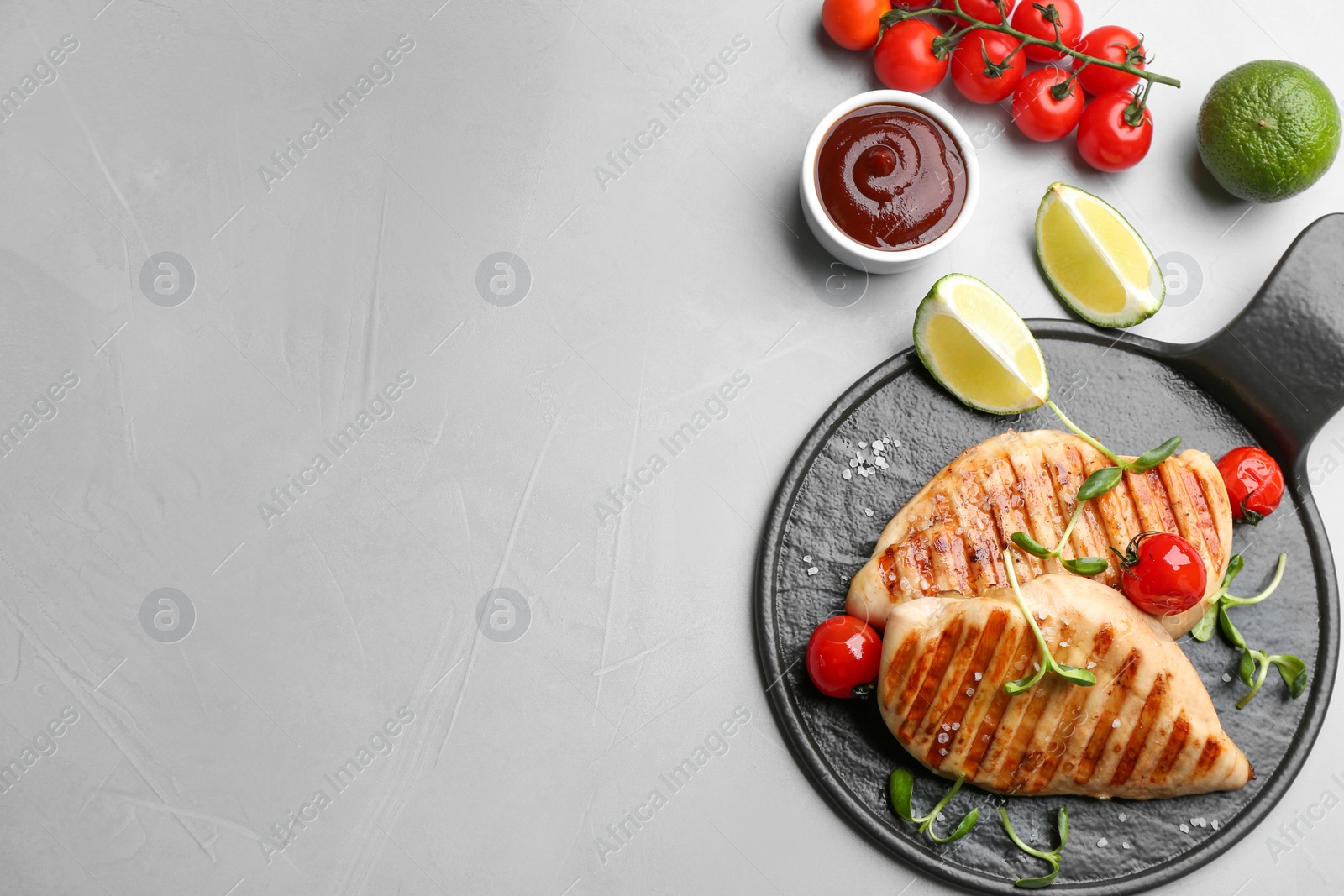 Photo of Flat lay composition of tasty grilled chicken fillets on light grey table. Space for text
