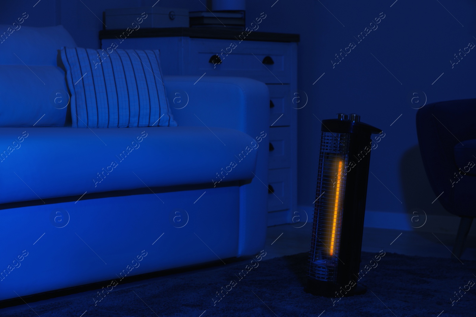 Photo of Electric infrared heater in dark living room at night